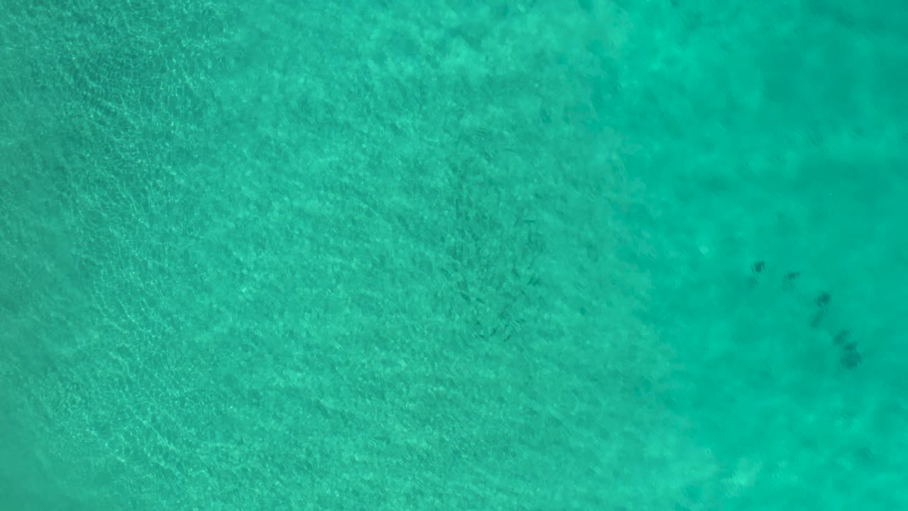 Clear blue-green water with a small group of people near the upper right.