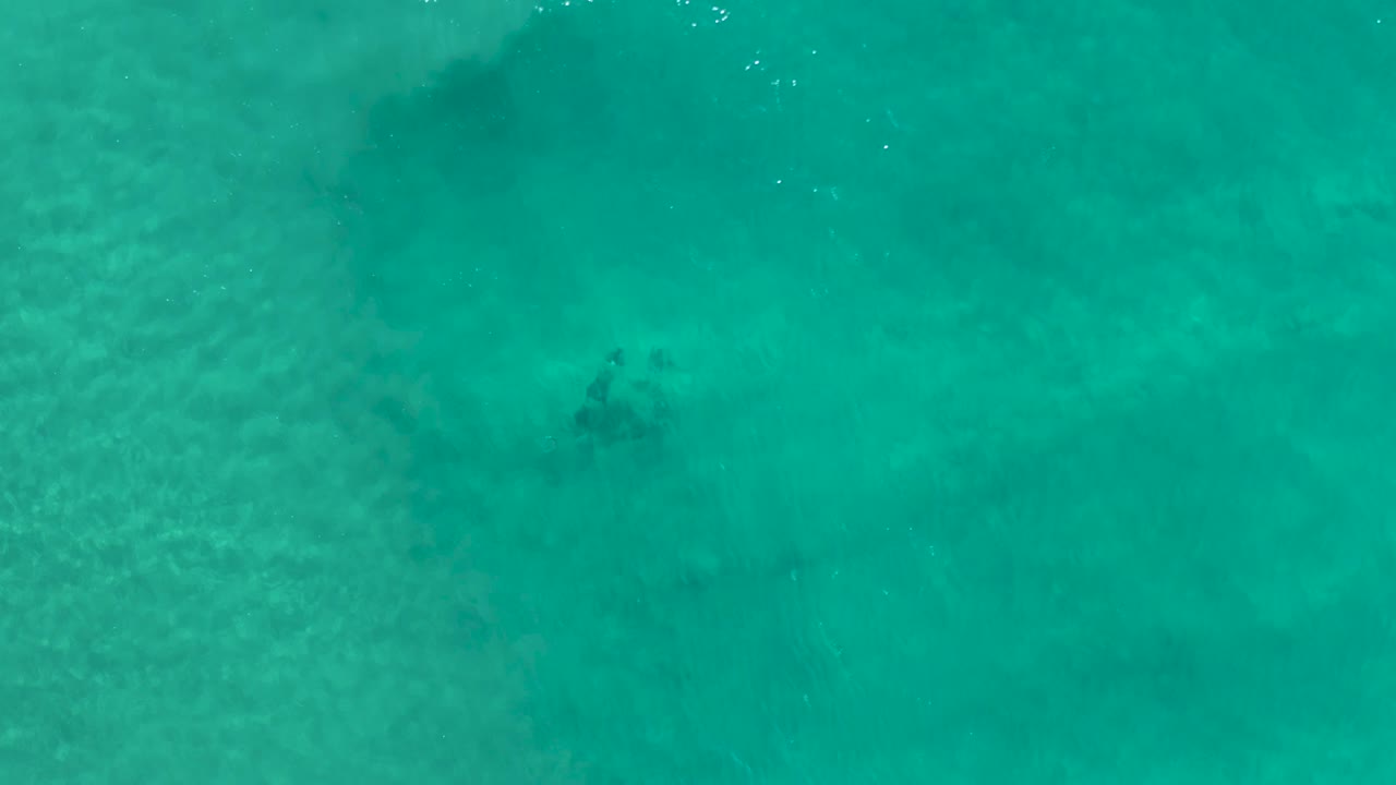 Aerial ocean surface with soft ripples and mottled teal water.