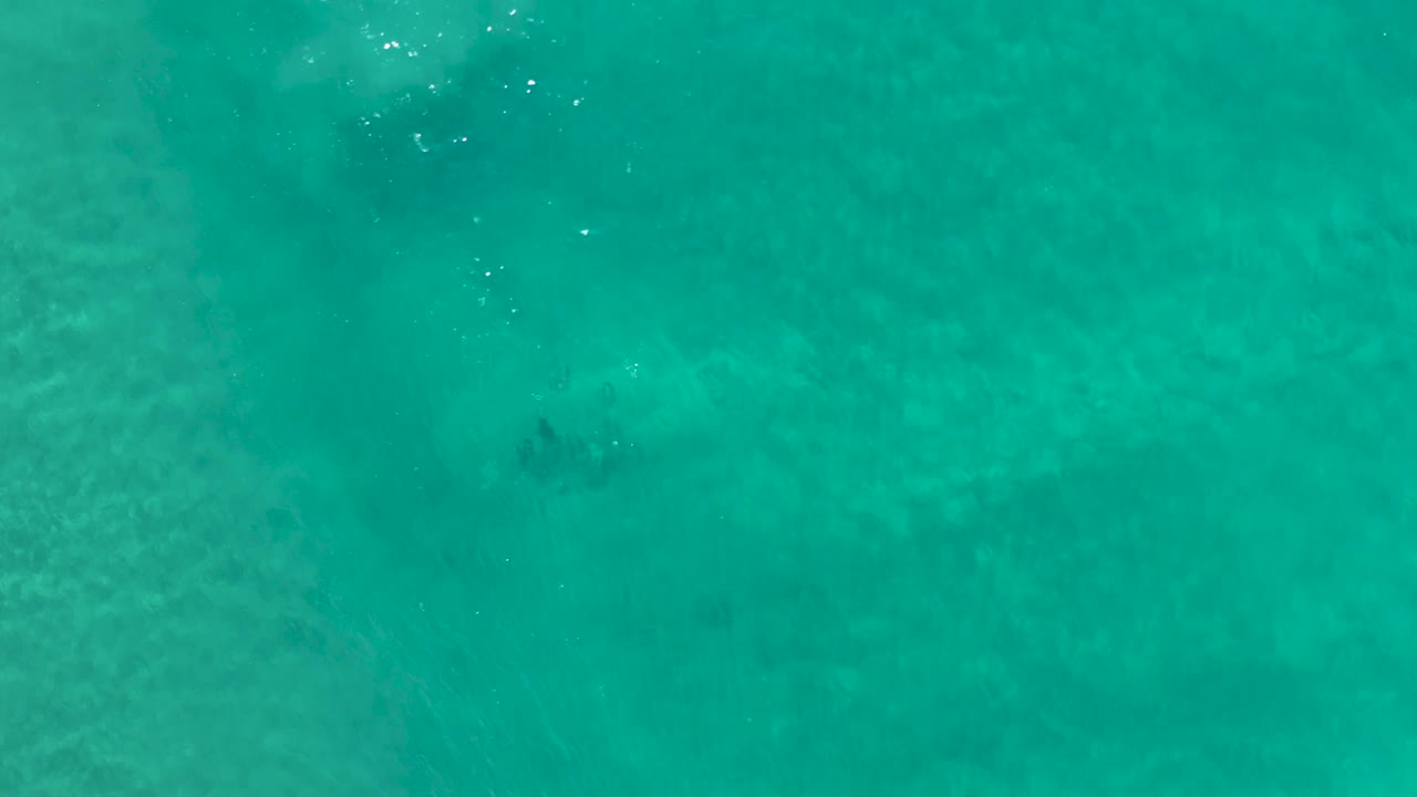 Top-down Los Cabos ocean frame with a darker current shape visible through turquoise water and no visible people.
