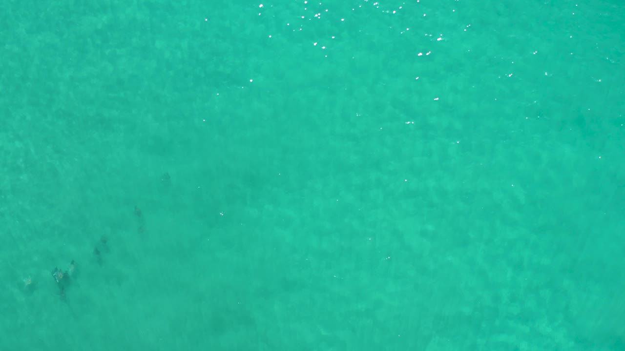 Aerial-looking view of turquoise Los Cabos water with soft shimmer across the top edge and no visible people, boats, or shoreline.