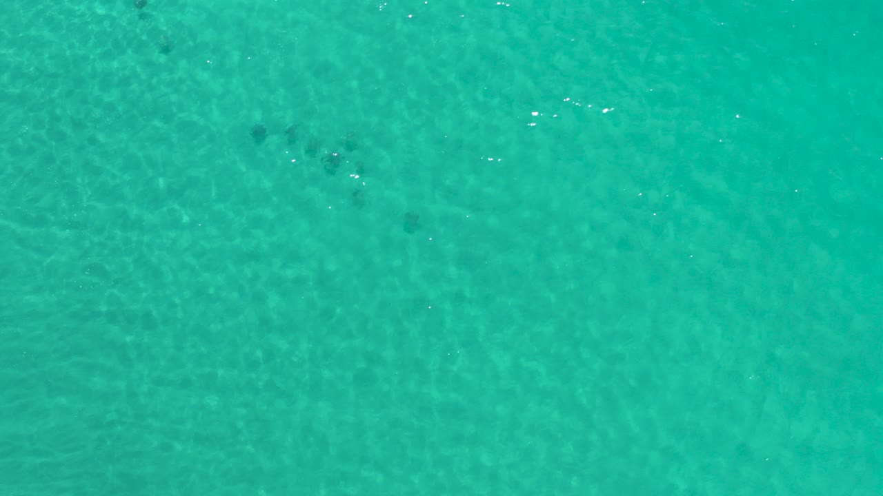 Turquoise ocean water seen from above with faint darker patches.