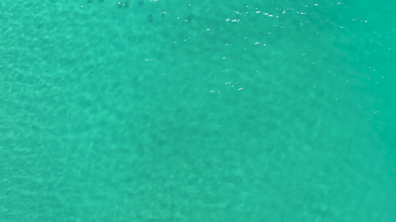 Turquoise Los Cabos water fills the frame with soft ripple bands and muted underwater texture, with no visible people.