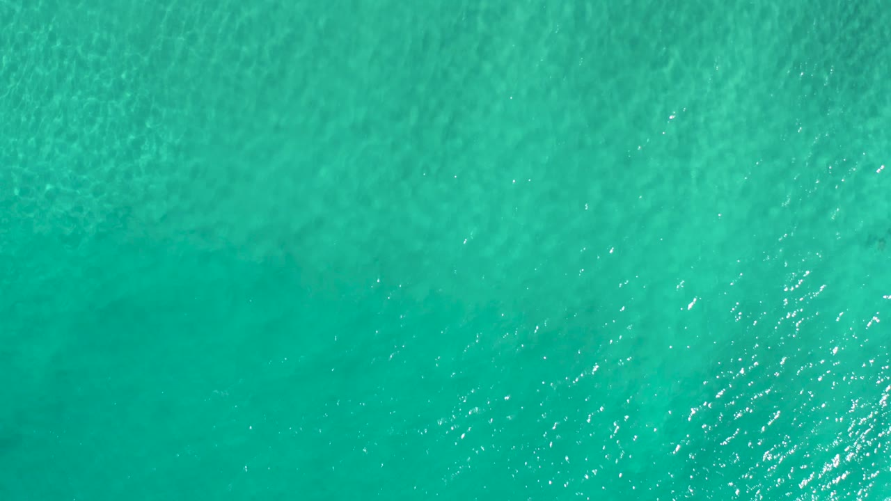 Top-down Los Cabos ocean water with turquoise color, scattered sunlight sparkle, and no visible people.