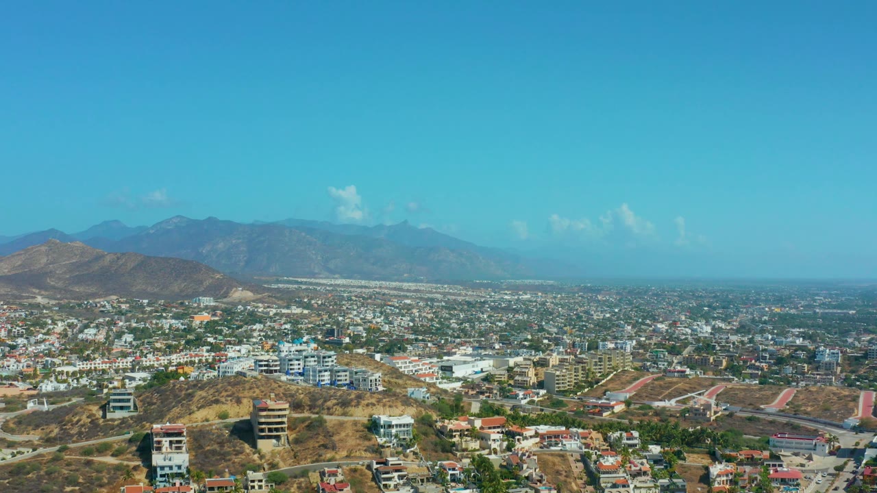 Wide Los Cabos aerial with dry foreground ridge and dense urban area
