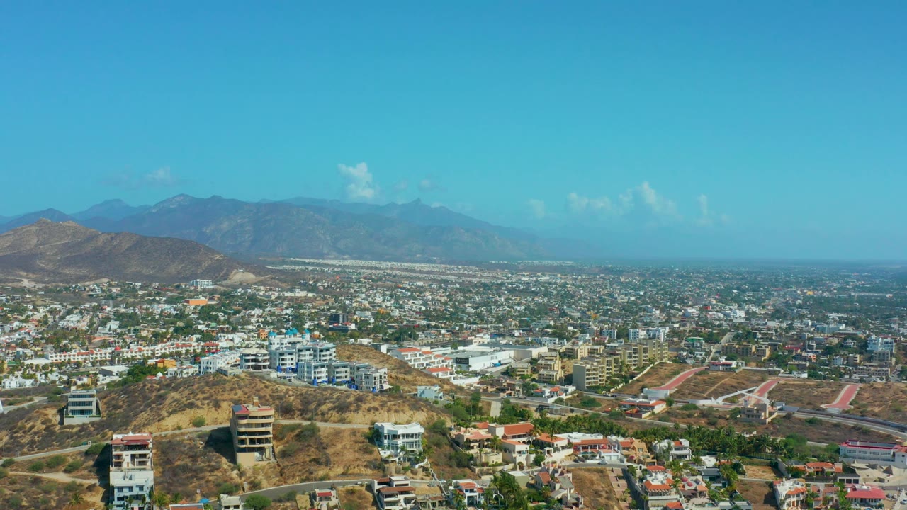 Aerial city view with desert hills in front and mountains on the horizon.