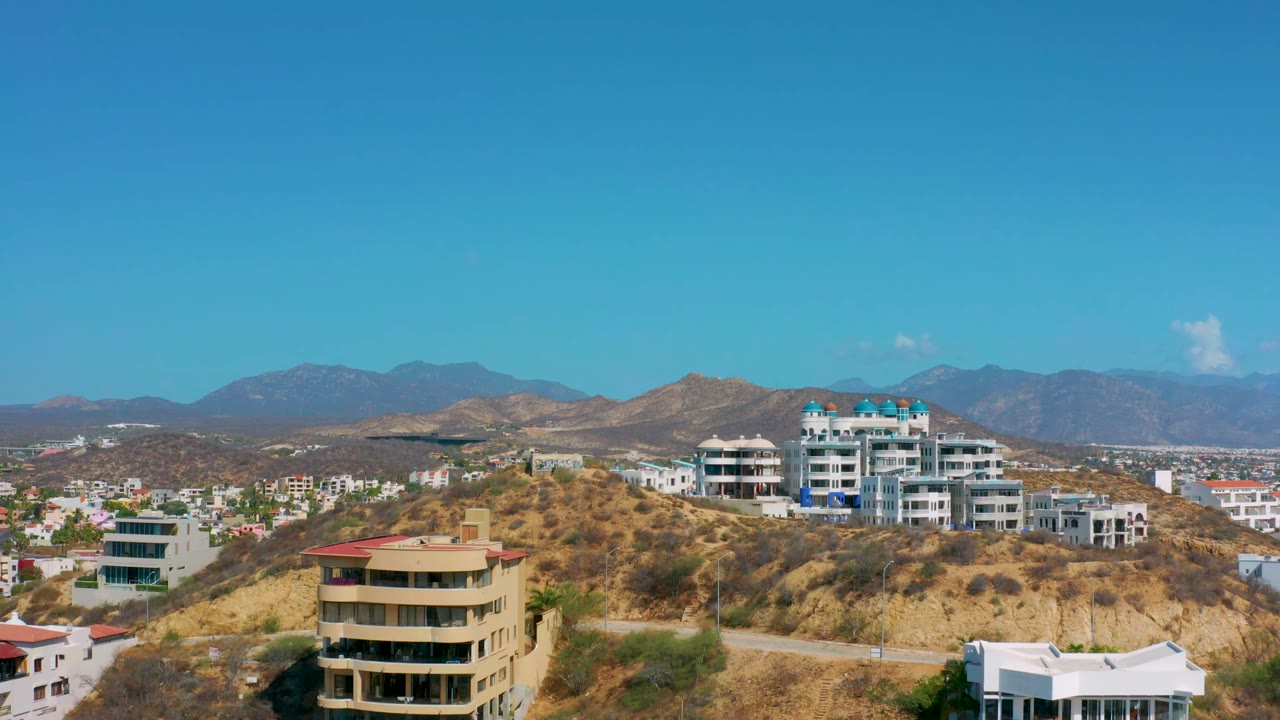 Residential hillside with condos, houses, and mountains in the distance