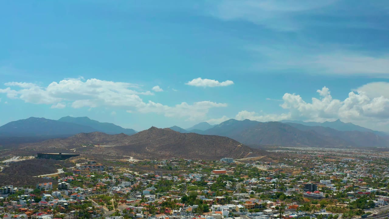 Town rooftops and arid hills under a broad blue sky