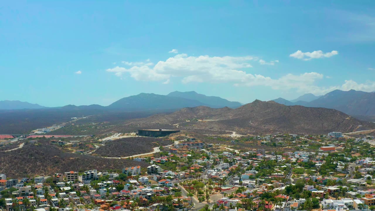 Bird's eye view of homes, hillside terrain, and distant mountains.