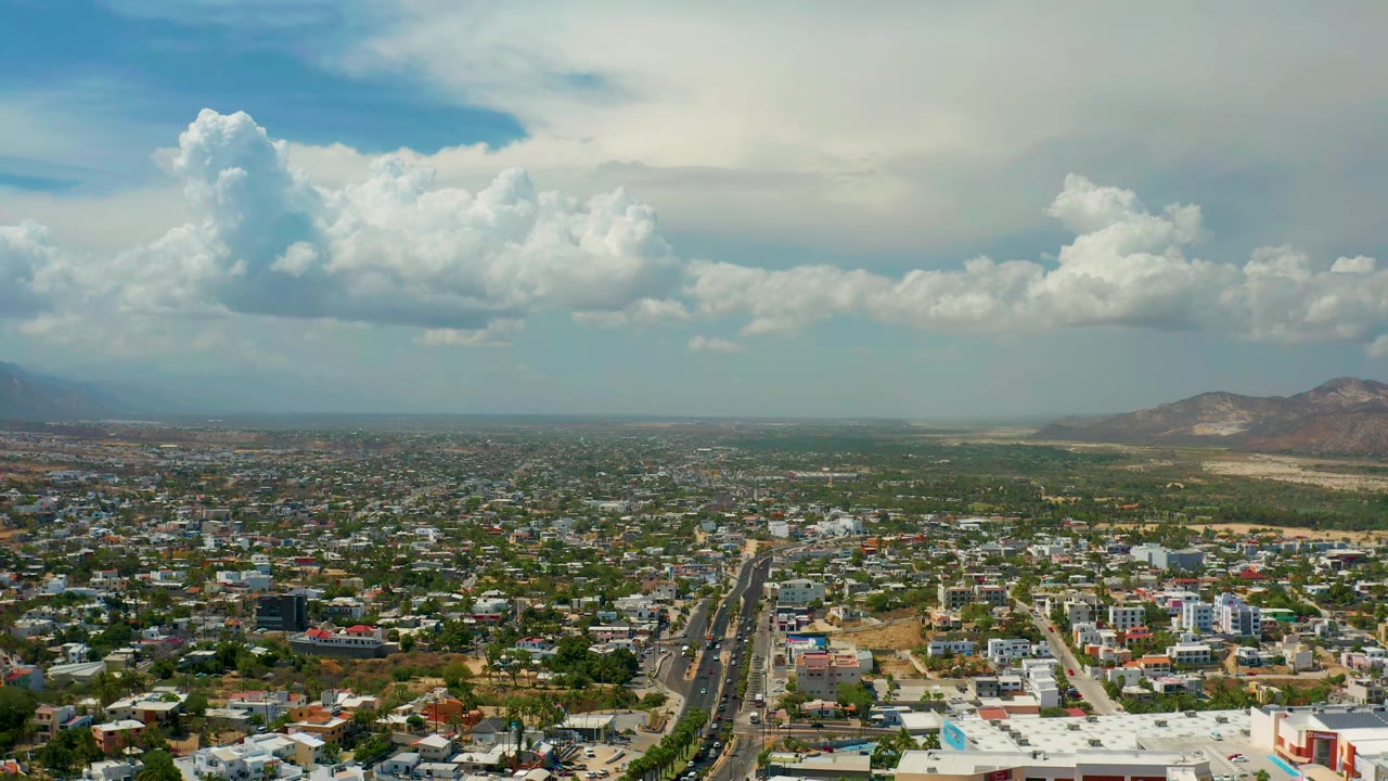 High city view with a central roadway and cloud bank over distant mountains.