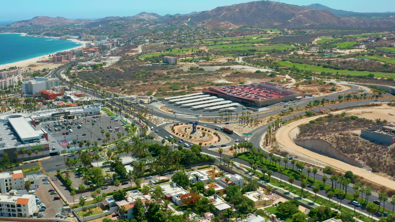 High aerial view of a roundabout, commercial buildings, coast, and hills.