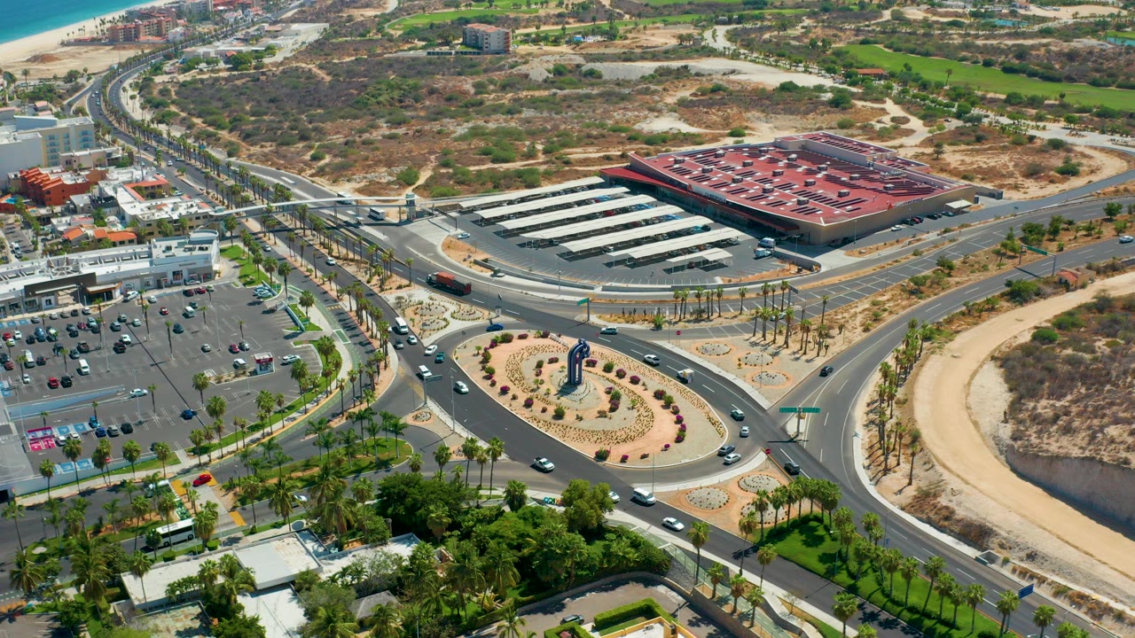 Aerial view of cars moving around a landscaped roundabout near a parking lot.