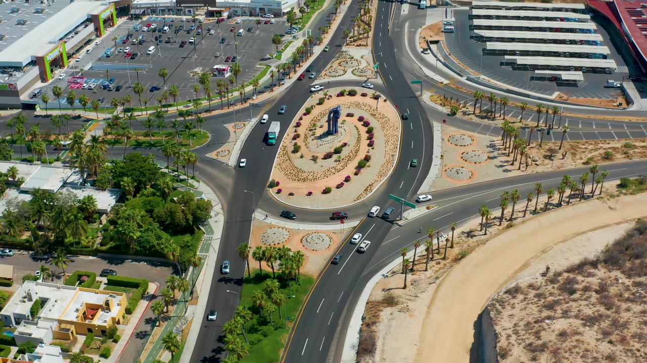 Overhead roundabout with cars, palms, parking areas, and desert landscaping.