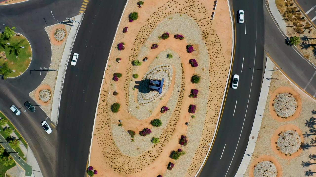 Aerial view of cars moving around a landscaped road circle.