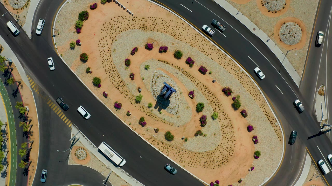 Aerial road scene with cars curving around a planted median.