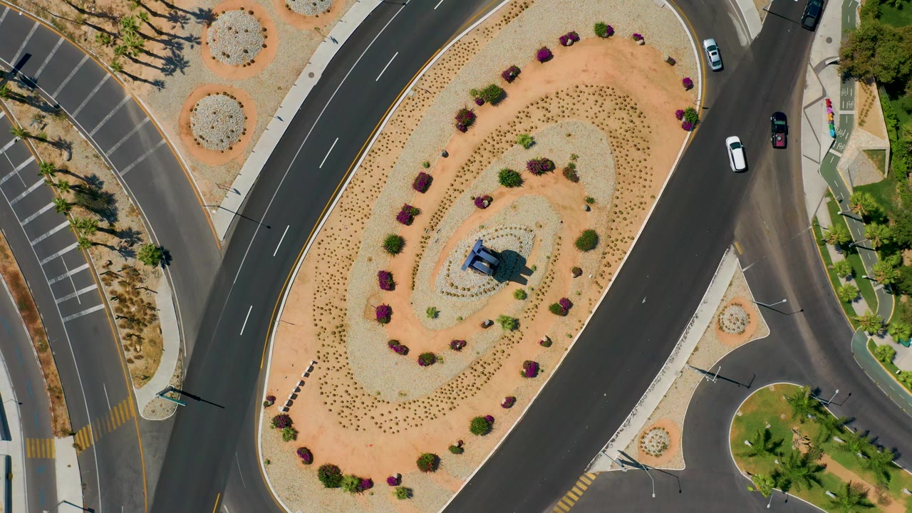 Drone view of a landscaped circular intersection with several cars.