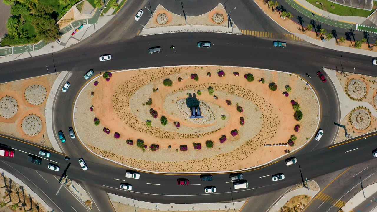 Overhead view of cars circling a landscaped roundabout.