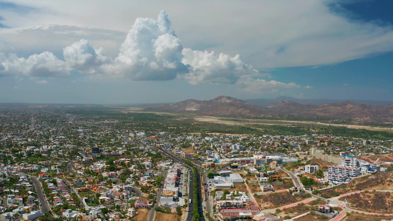 Aerial view over roads and neighborhoods toward distant hills.