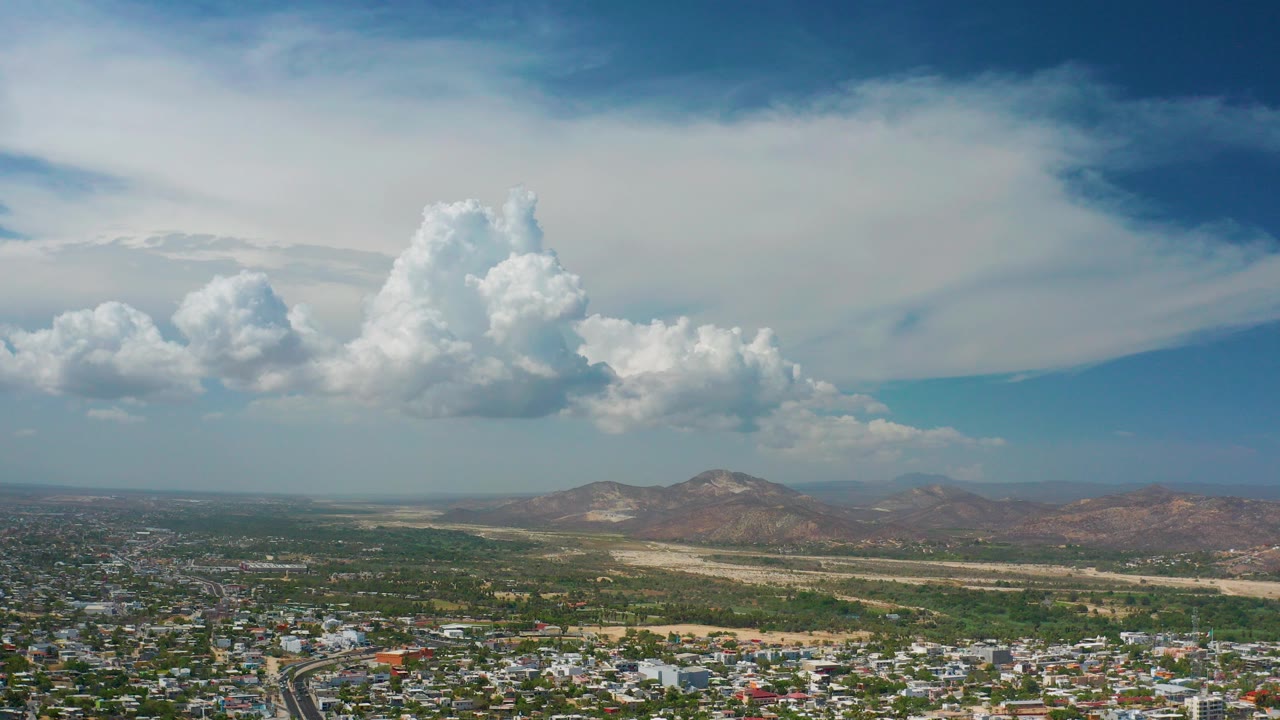 Aerial view of clouds over low mountains and town edge