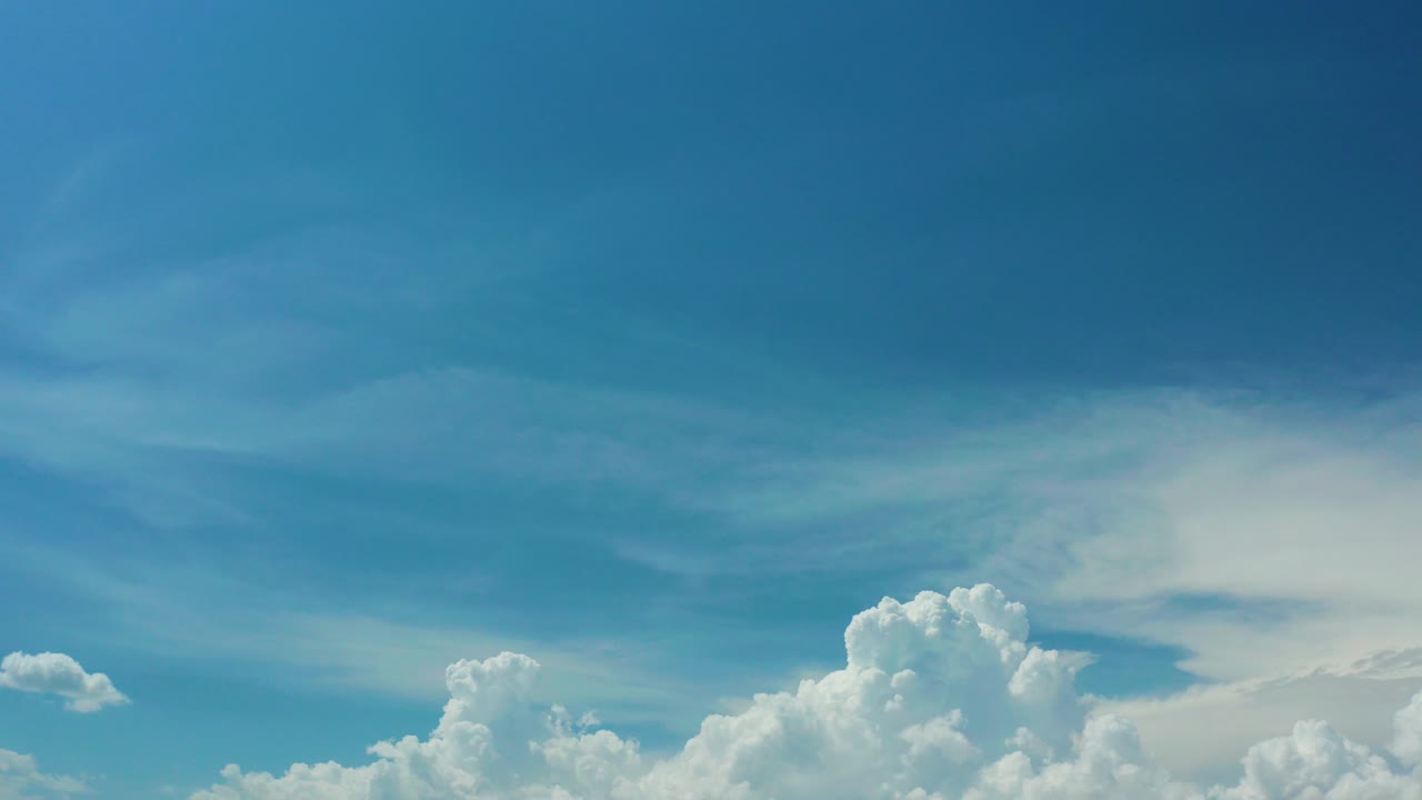 Blue sky with white cumulus clouds near the lower edge