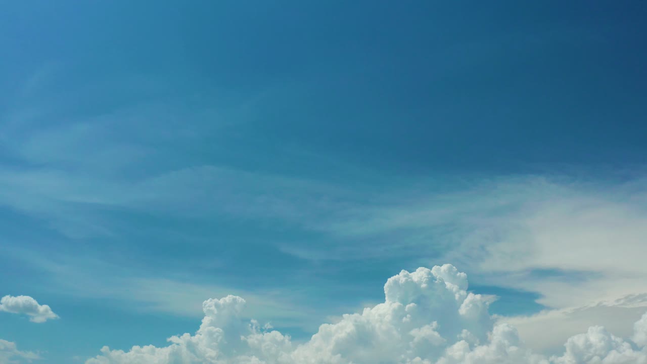 A bright Los Cabos cloud bank sits along the lower portion of the frame beneath layered blue sky and pale wisps, with no visible people.