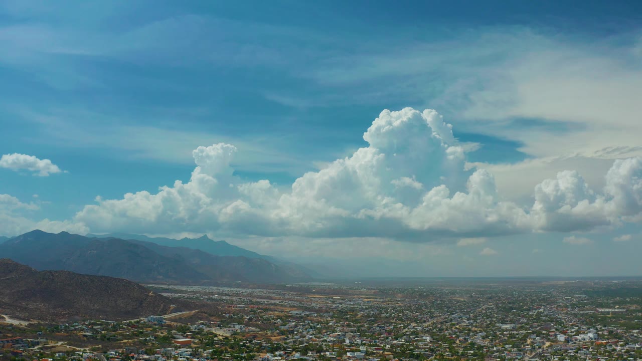 Valley town beneath blue sky and tall white clouds