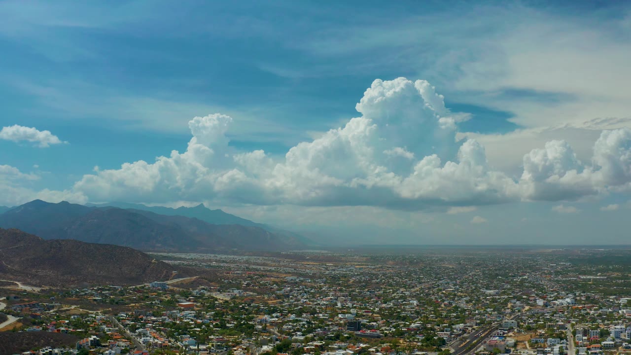 Elevated view across city blocks toward hills and clouds.