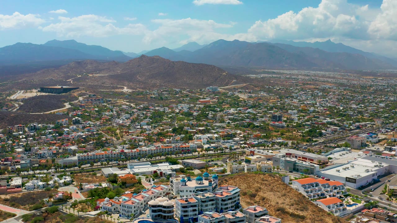 Aerial city panorama with roads, trees, hills, and bright clouds