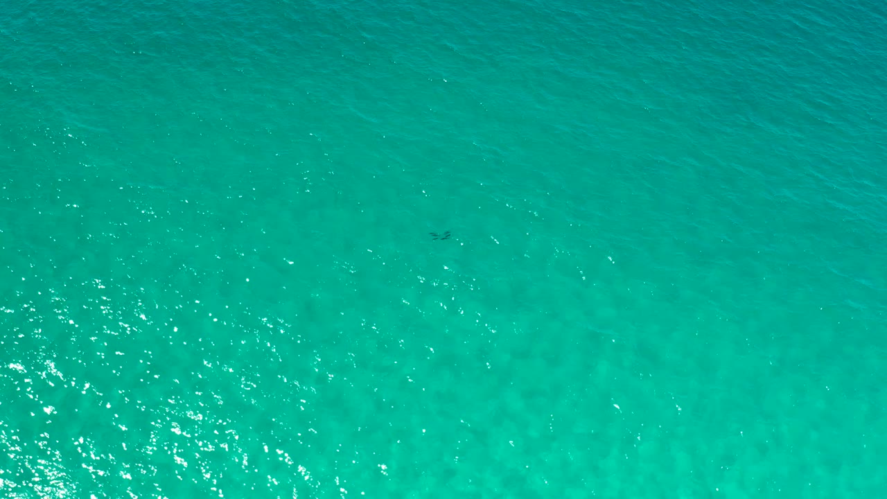 Clear teal ocean surface in Los Cabos, Mexico, seen from above with subtle darker patches under the water and no visible people.
