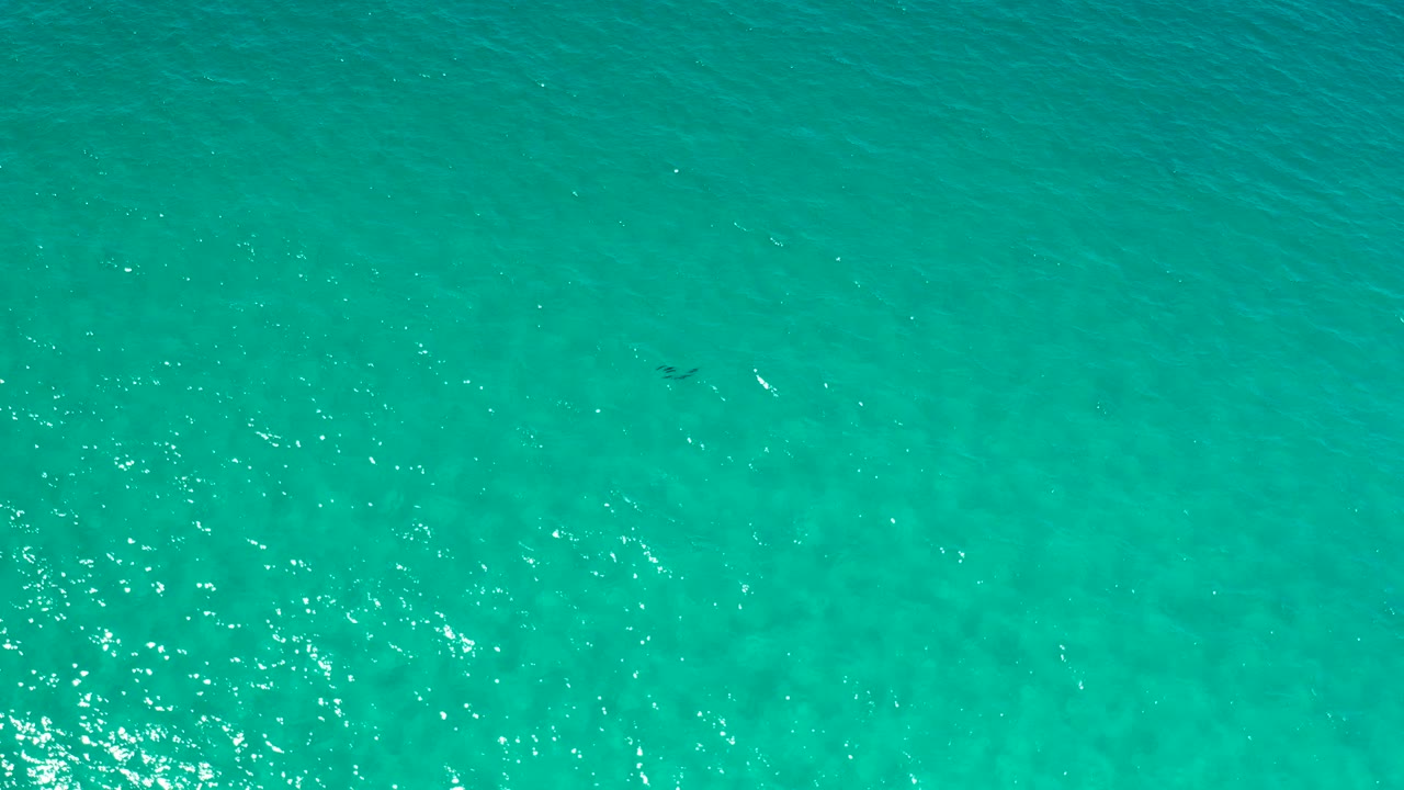 Aerial view of open ocean in Los Cabos, Mexico, with a slightly darker teal band across the upper area and no visible people.