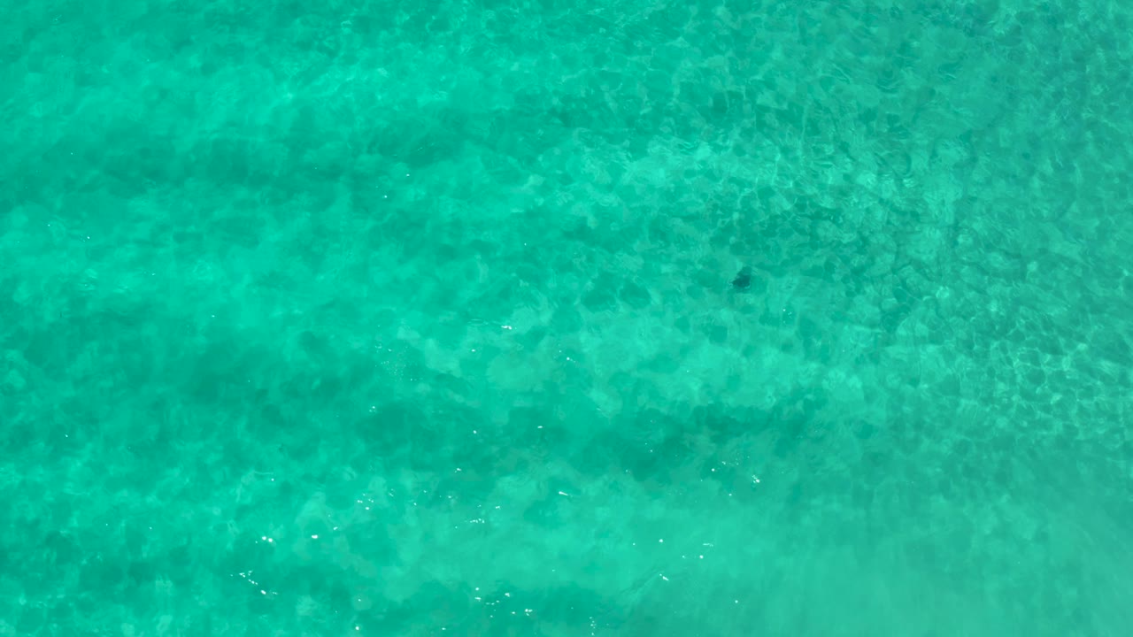 Green-blue ocean water fills the frame in Los Cabos, Mexico, with a patterned seabed and no visible people.