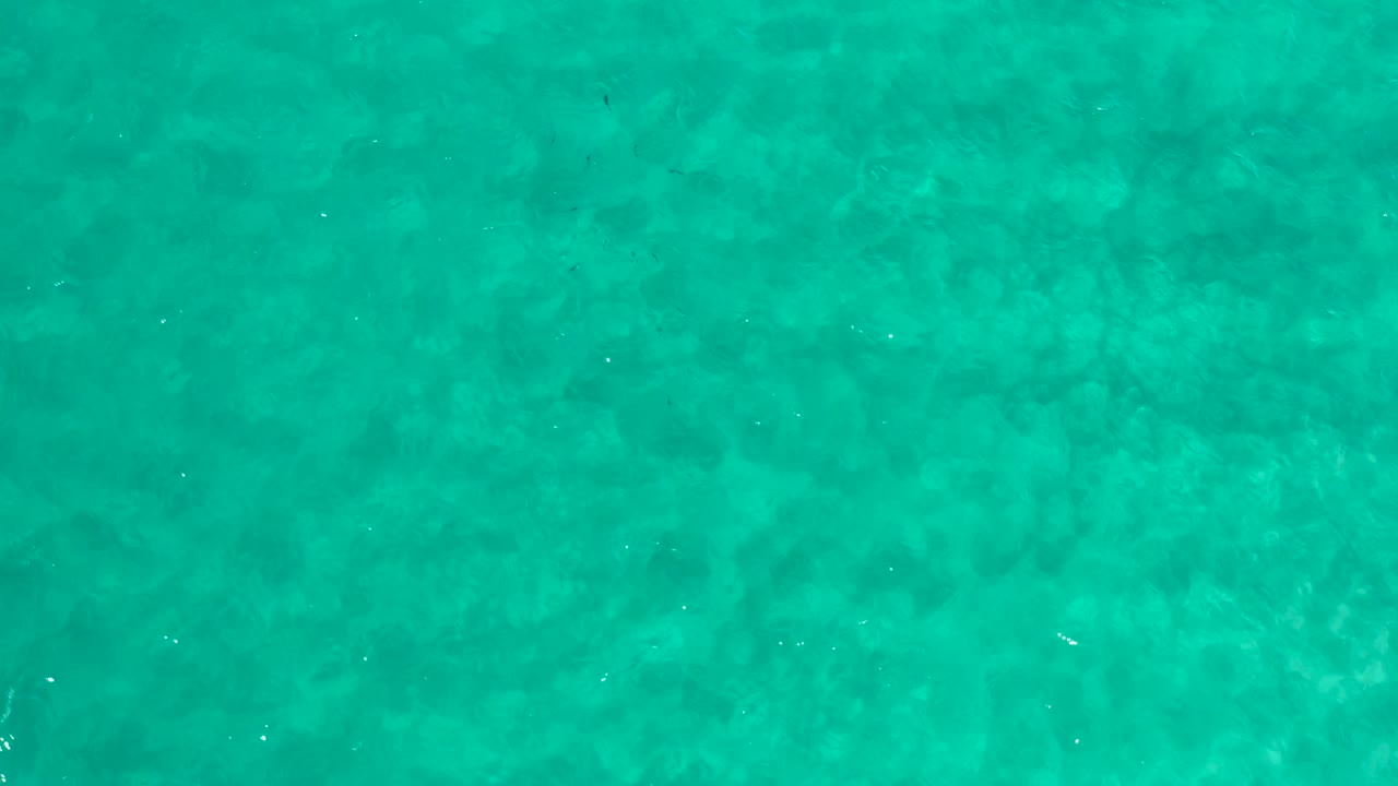 Clear teal water with mottled seabed tones.