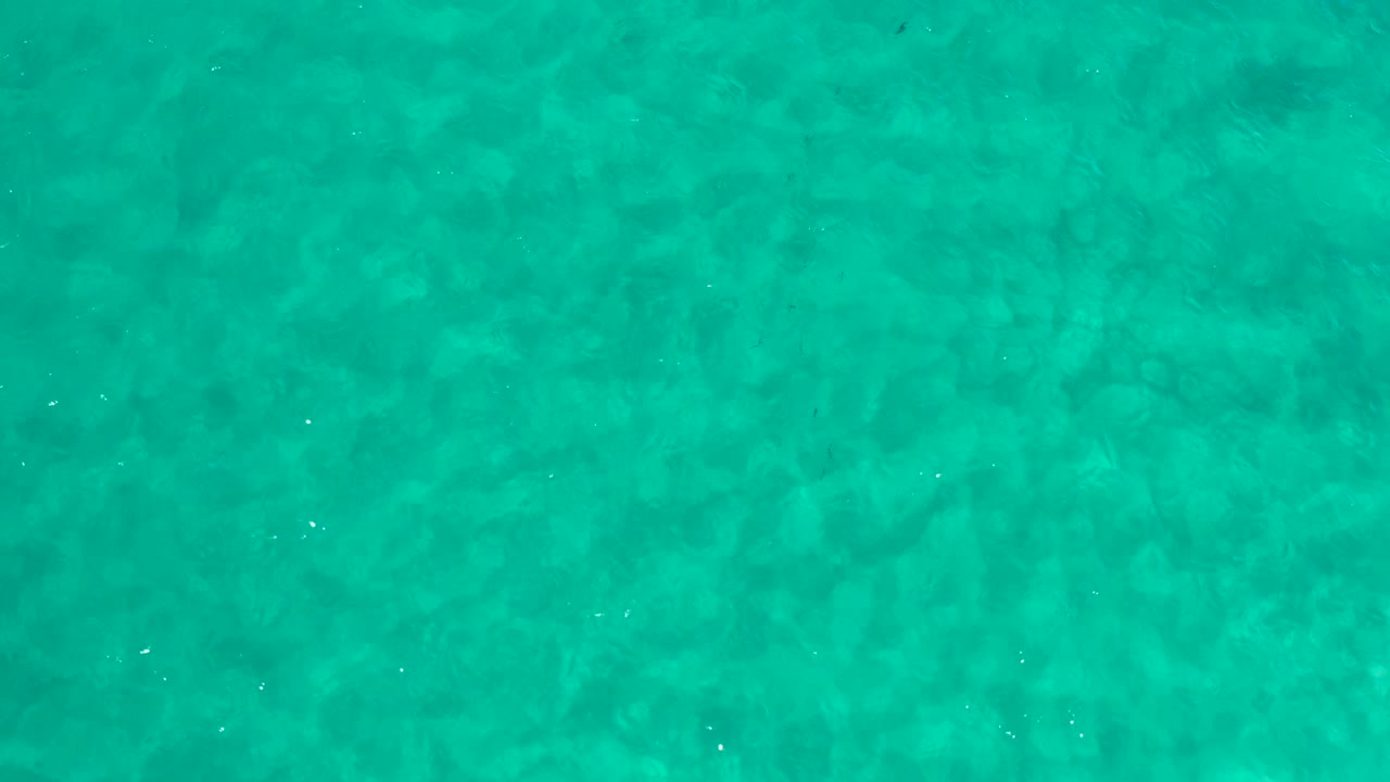 Top-down Los Cabos water frame with turquoise surface texture, scattered white glints, and no visible people.
