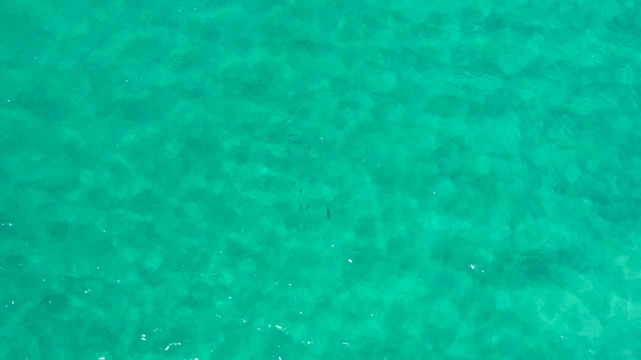 Top-down view of turquoise ocean water in Los Cabos, Mexico, with soft horizontal ripple bands and no visible people.