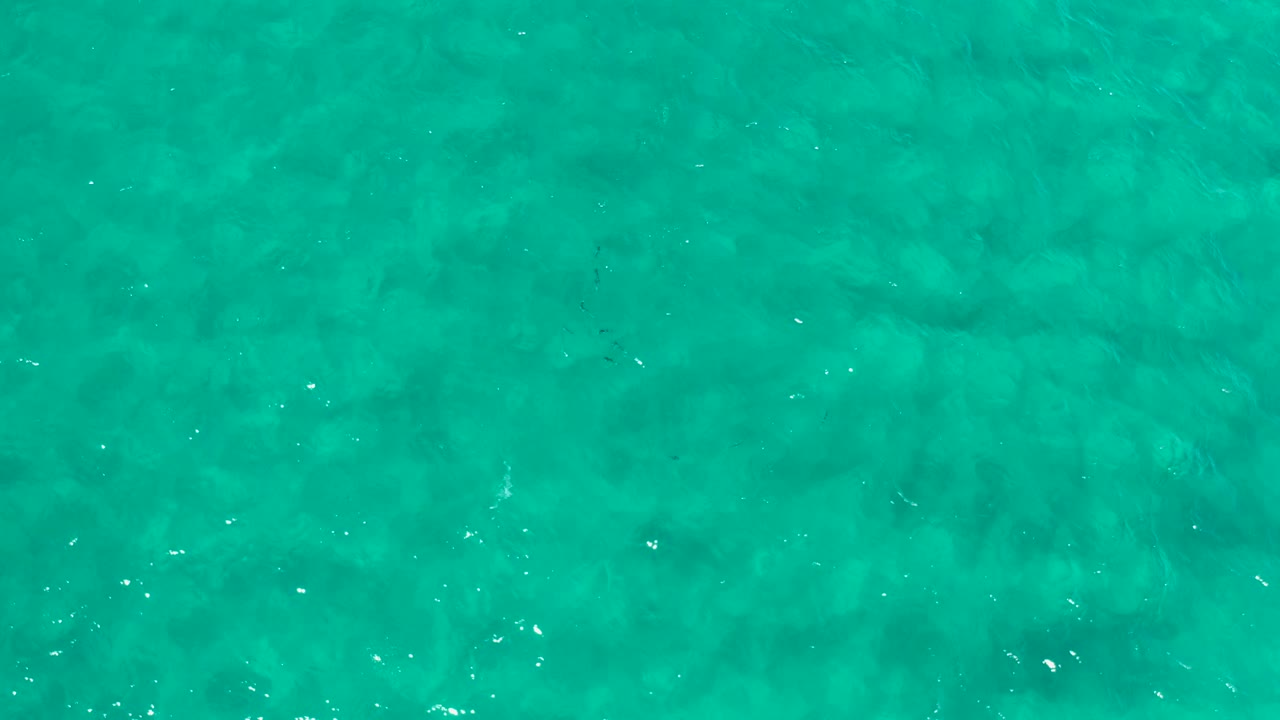 Blue-green ocean surface in Los Cabos, Mexico, seen from above with scattered white reflections and no visible people.