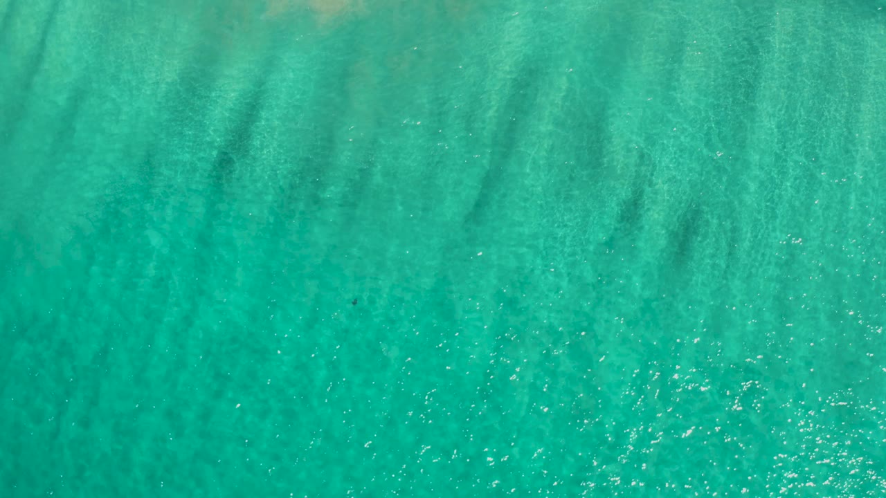 Blue-green Los Cabos ocean surface fills the frame, with ripples catching sunlight and no visible people, land, or boats.