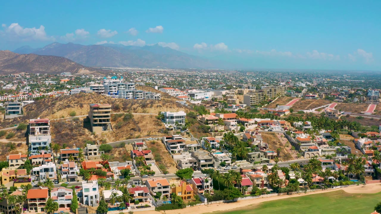 Third frame shows a broad Los Cabos, Mexico aerial with hillside villas in the foreground, pale roads across dry slopes, distant urban neighborhoods, and no visible people.