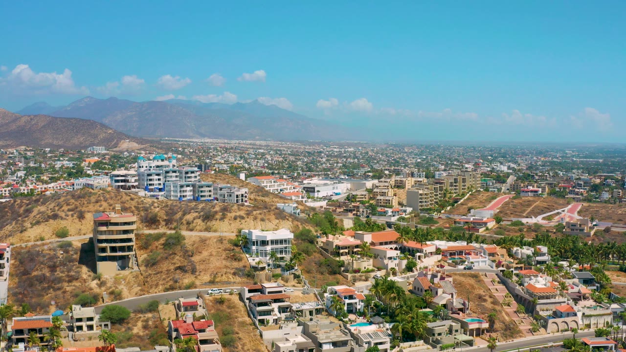 Aerial view across hillside buildings toward a hazy mountain horizon.