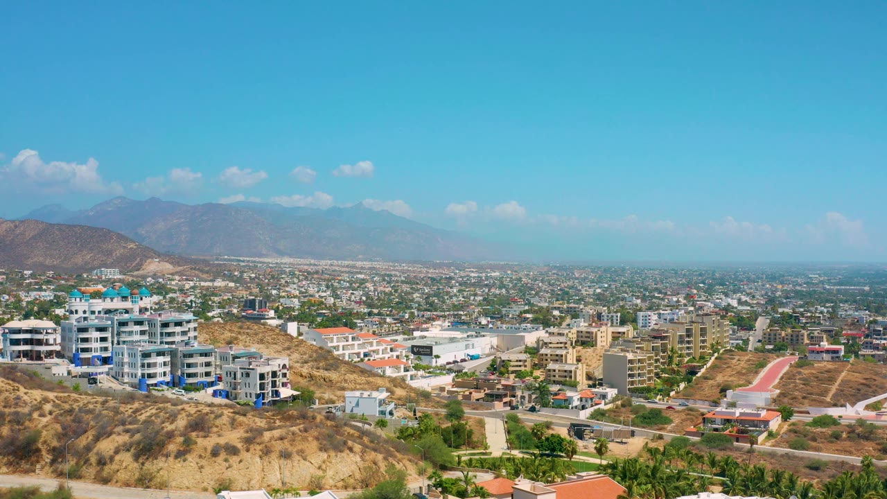 Panoramic aerial view of Los Cabos buildings and valley with mountains in the distance.