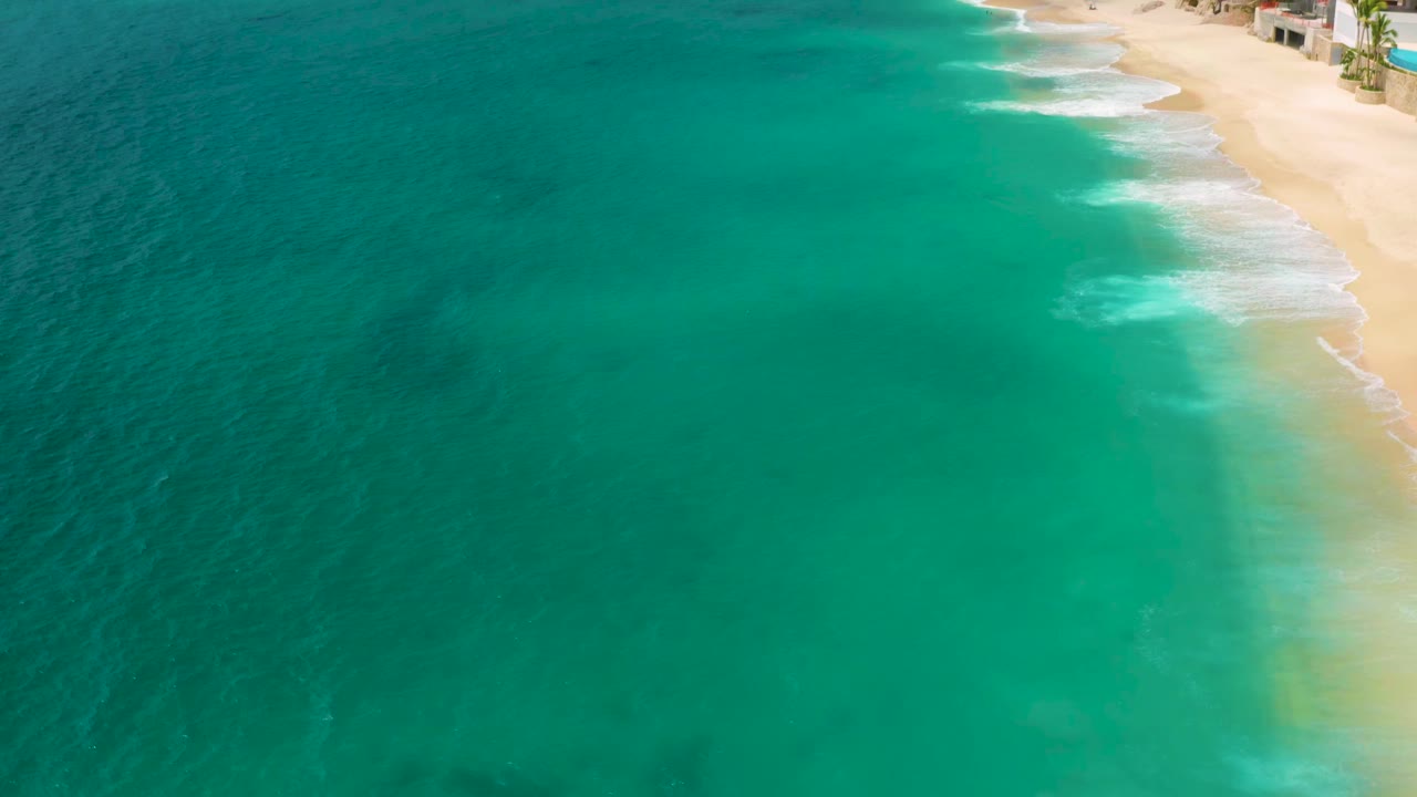 Aerial shoreline with green water and pale sand