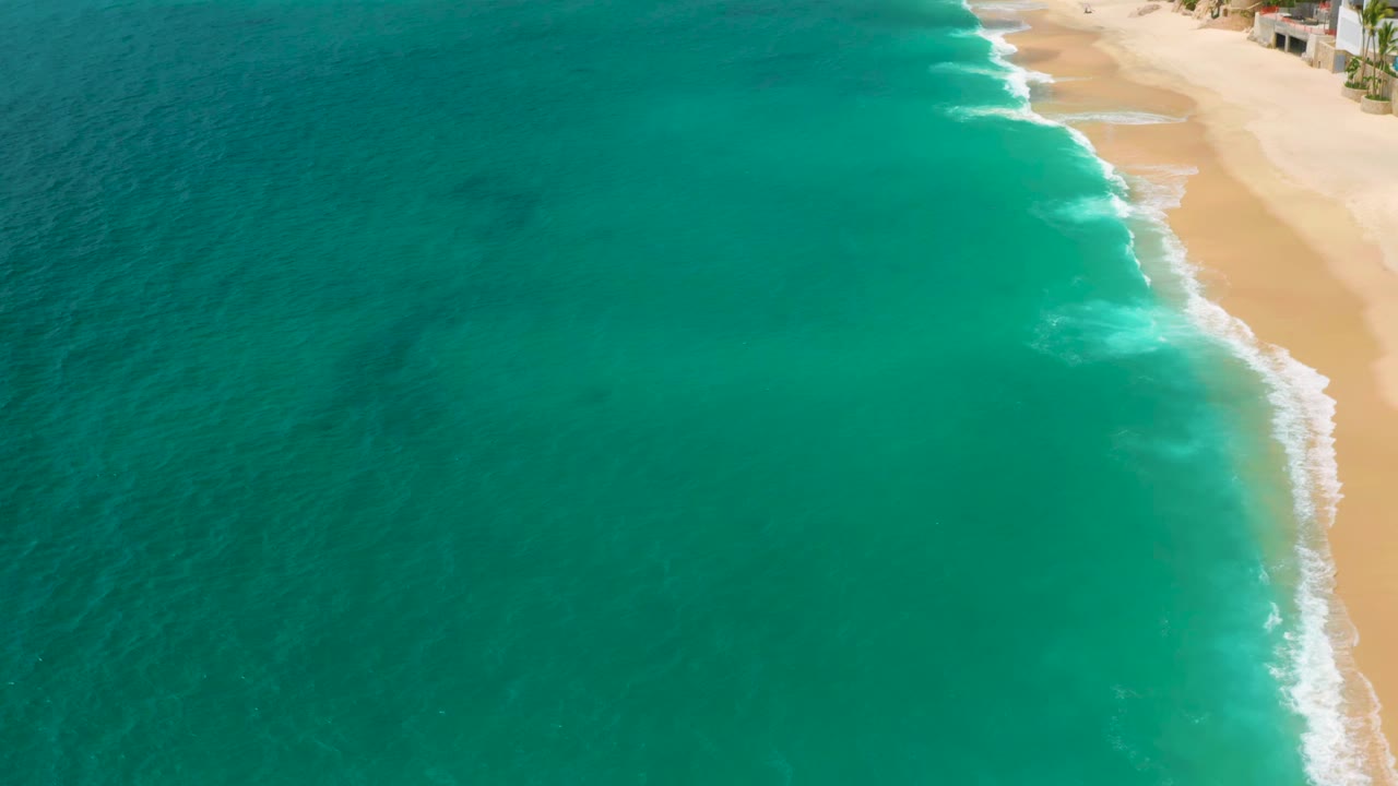 Blue green water rolling onto a pale beach