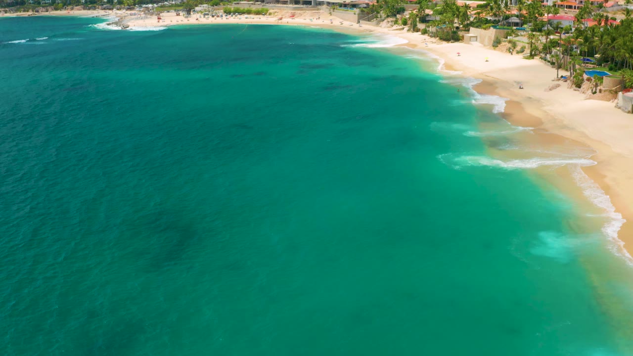 Turquoise sea and a curved sandy beach seen from above.