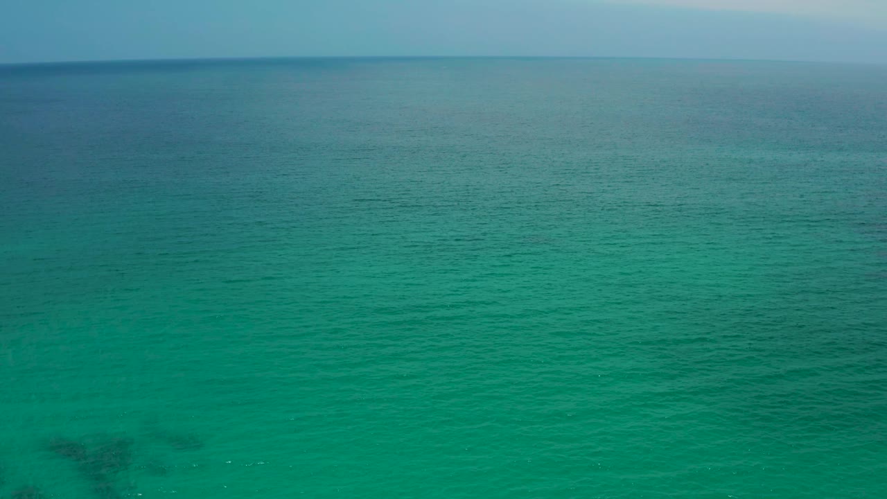 A green ocean surface fills the frame at Palmilla Beach Cabo, Mexico, with the blue horizon near the top and no visible people or vessels.