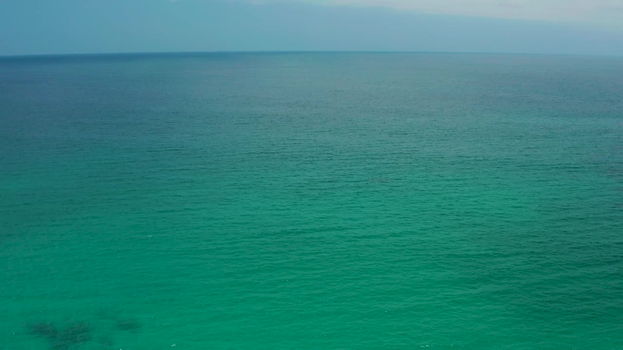 Open turquoise water stretches toward a level horizon at Palmilla Beach Cabo, Mexico, with a thin pale sky band and no visible people.