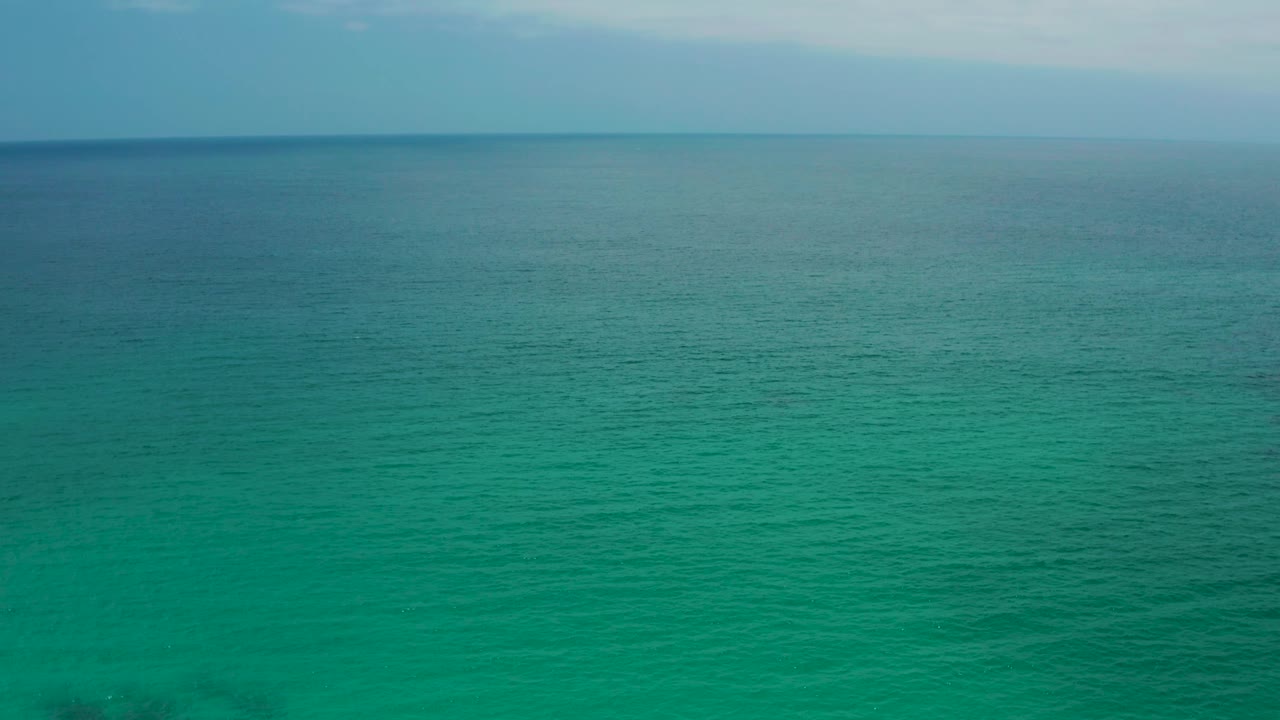 Green-blue ocean under light cloud cover at Palmilla Beach Cabo, Mexico, with soft water texture across the foreground and no visible people.