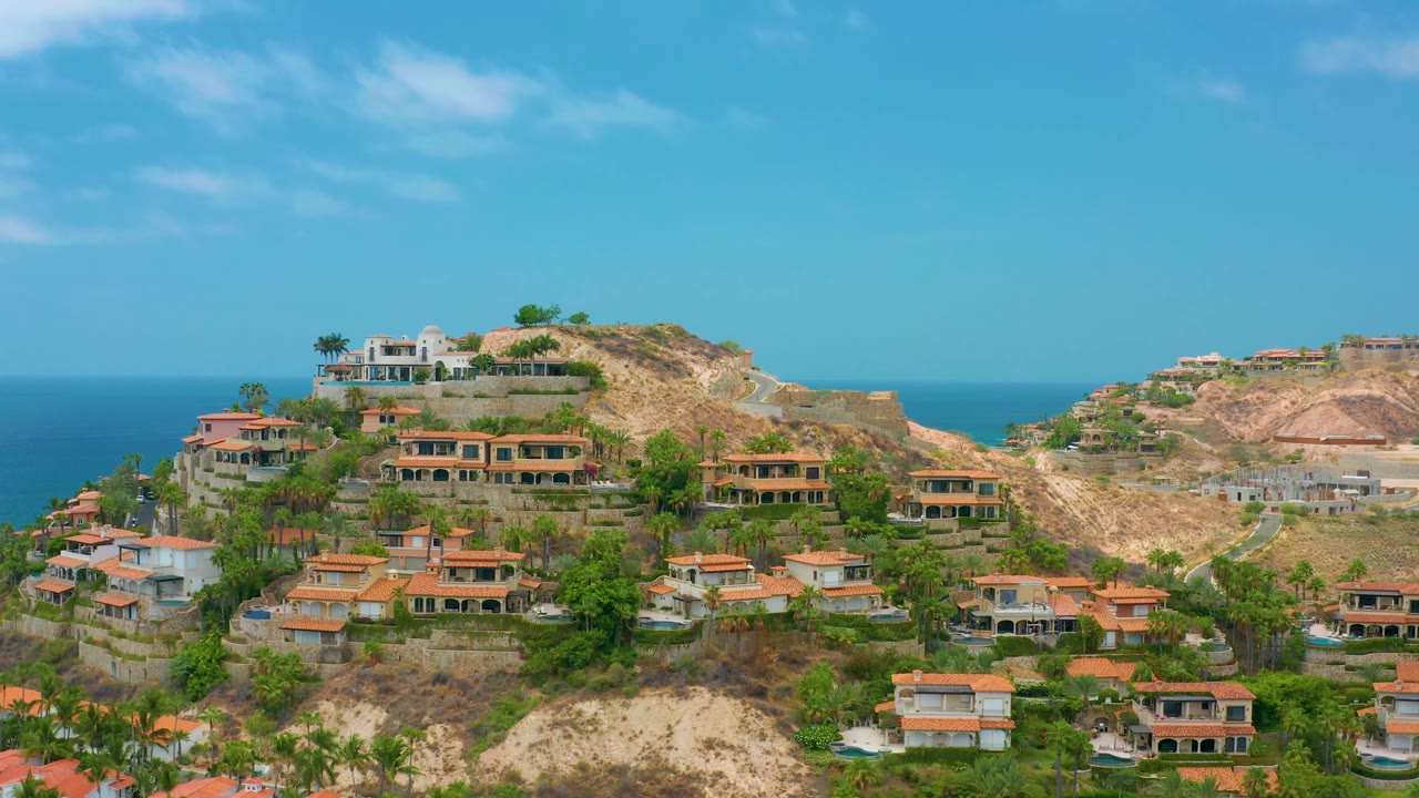 Coastal hillside homes under bright blue sky