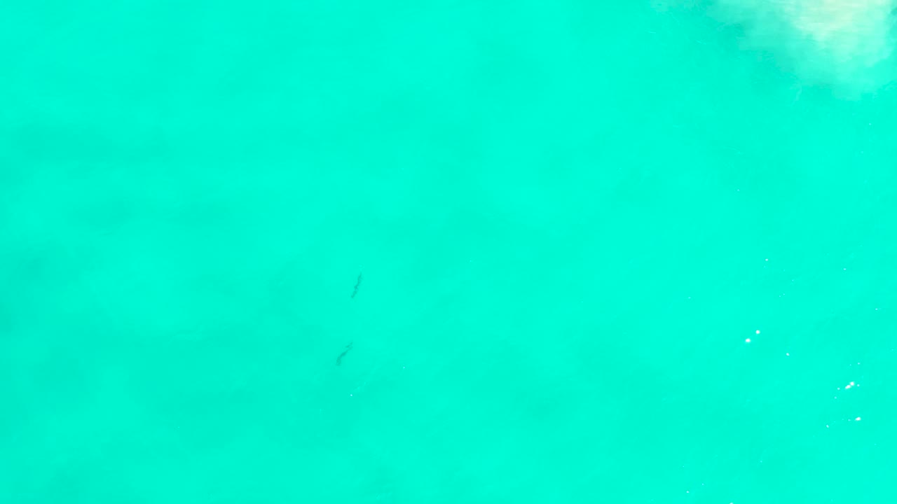 A nearly full-frame view of blue-green sea water in San Jose Del Cabo shows faint underwater marks, soft surface brightness, and no visible people.
