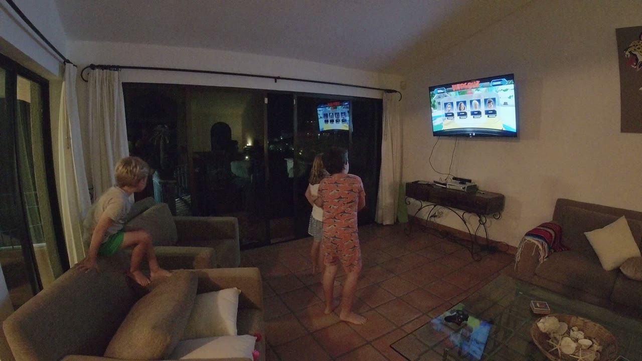 Children in a living room watching a wall-mounted television