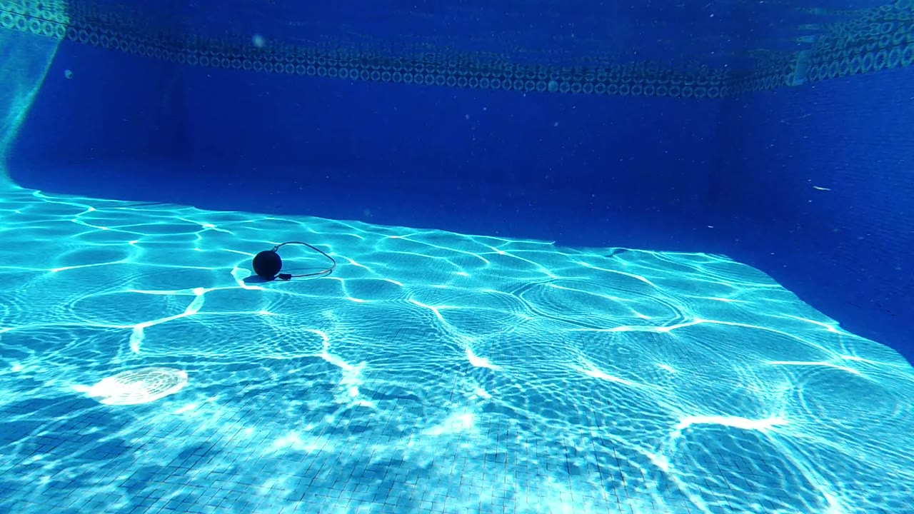 At the start of the Los Cabos pool clip, bright caustic lines cover the blue pool floor while a dark round object with a cord rests underwater, with no visible people.