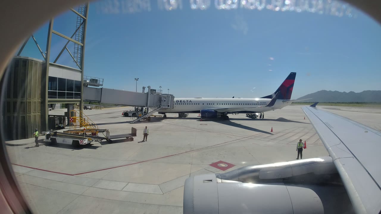 Passenger-window view of a Delta aircraft at an airport gate.