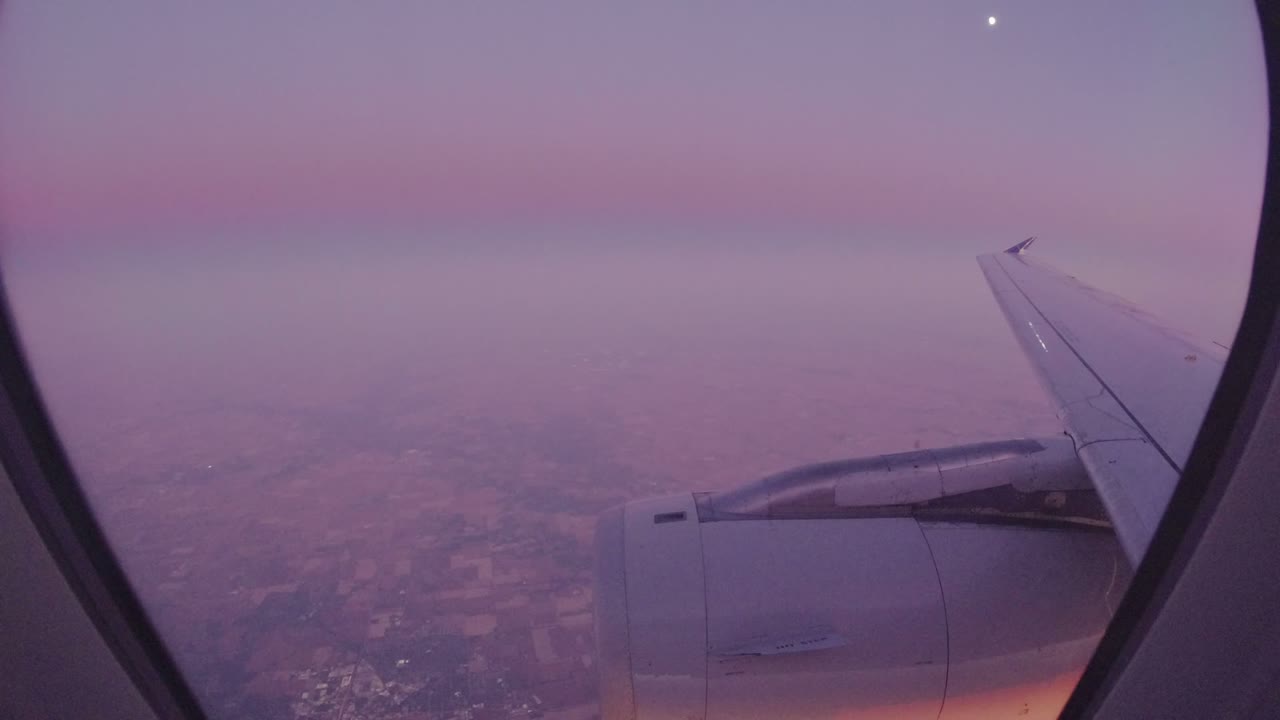 A Los Cabos, Mexico passenger-window frame shows the wing angled across the right side, engine below it, hazy terrain beneath, and no visible people.
